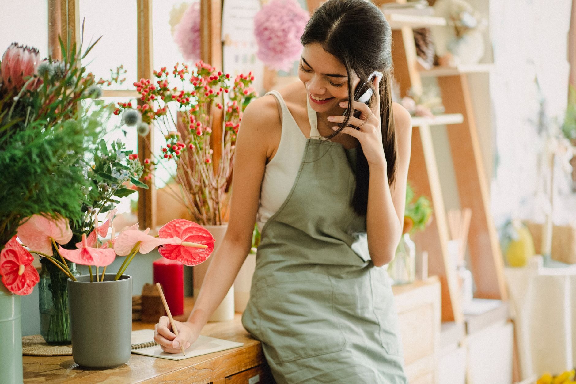 A flower-shop owner on her phone at her counter, updating her business from the shop floor
