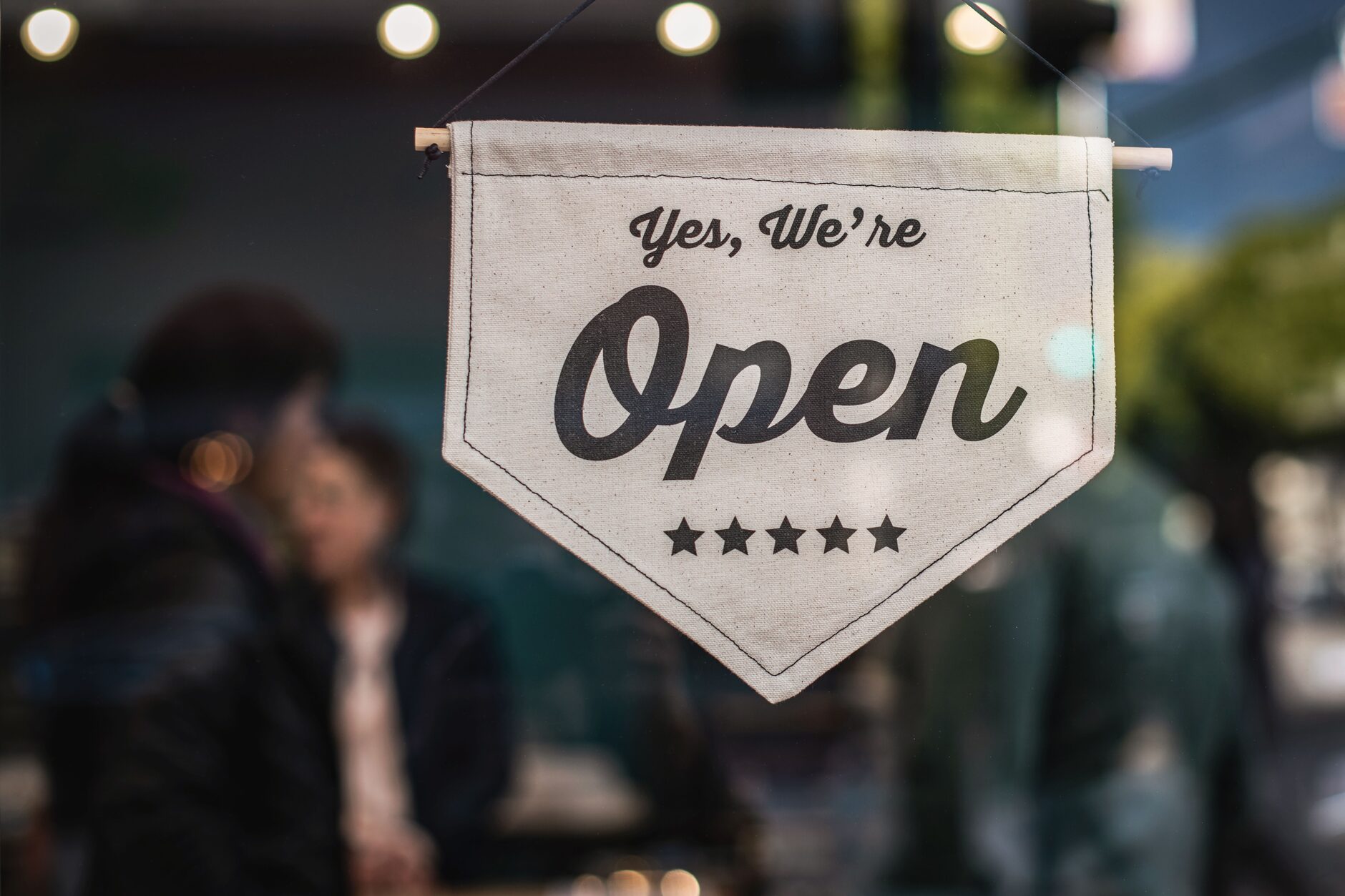 A 'Yes, We're Open' sign hanging in a small business storefront window